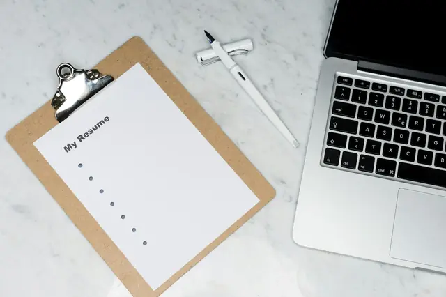 A checklist, folder and laptop arranged on a desk