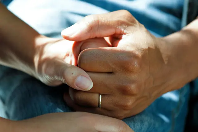 A close-up of hands gently holding another hand
